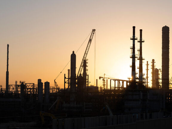 Silhouette de raffinerie avec colonnes et grues au coucher du soleil