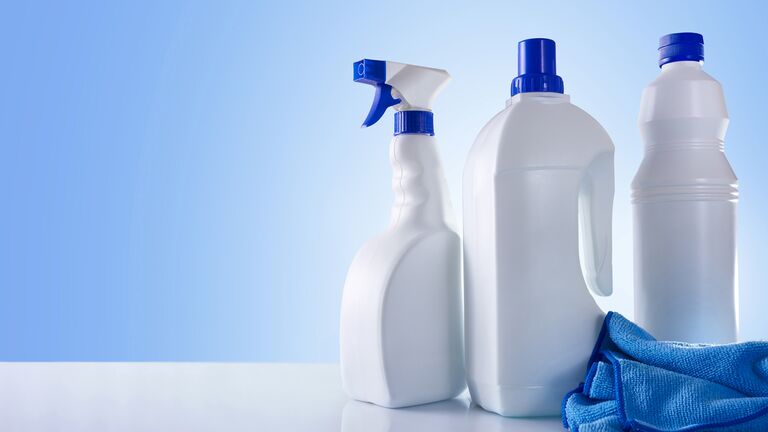 Three cleaning products in bottles, alongside a blue microfiber cloth