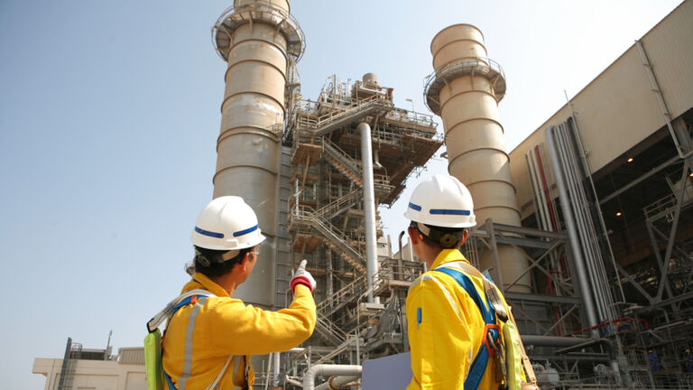 Two workers in safety gear onsite at a plant