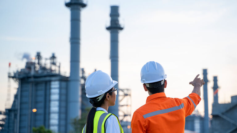 Refinery industry engineer working and discussing in front of an industrial factory