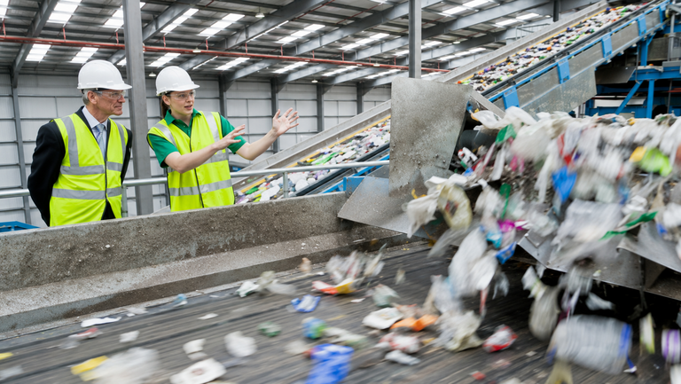 Two workers inside a large industrial recycling facility