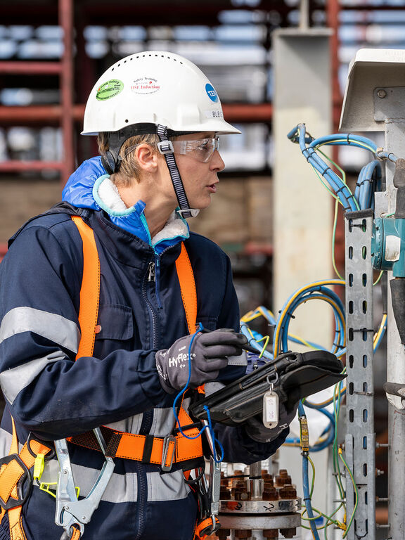 Two engineers in hard hats inspect industrial electrical equipment in a power plant, ensuring safe operations and maintenance