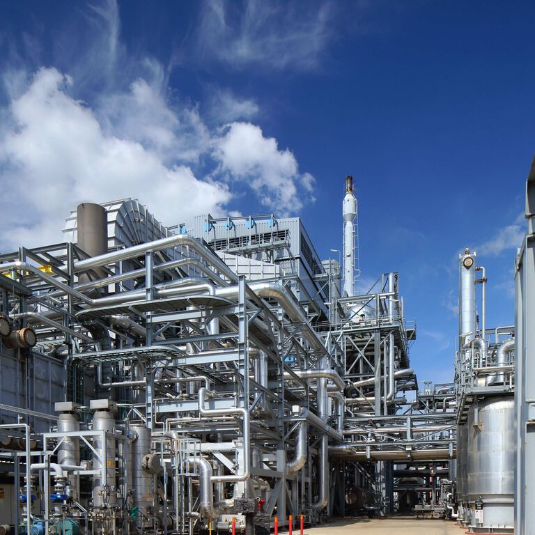 Usine industrielle avec des tuyaux et des structures métalliques sous un ciel bleu.