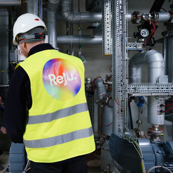 A worker inside Reju's Regeneration Hub, wearing a safety vest with Reju's logo on his back