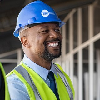 Un groupe de professionnels en gilets de sécurité et en casques discutant d'un projet sur un chantier de construction
