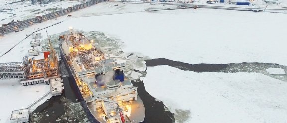Aerial shot of a ship navigating icy waters near the Yamal industrial complex, in the background