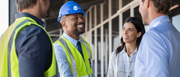 A group of professionals in safety vests and helmet discussing a project on a construction site