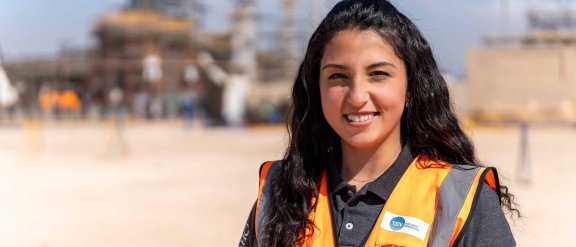 Jeune femme souriante en gilet de sécurité orange sur un chantier