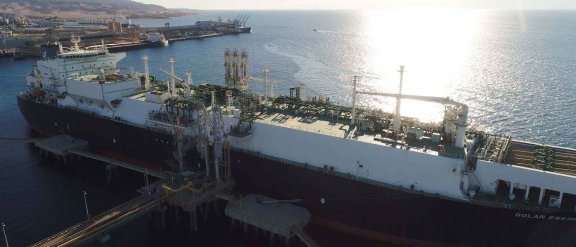 A boat is docked at a jetty, ready to be connected to loading arms to transfer energy.
