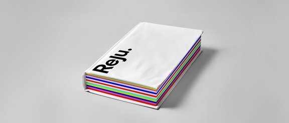 A notebook with Reju branding (logo, white cover, and colorful pages in various hues, visible along the edges)