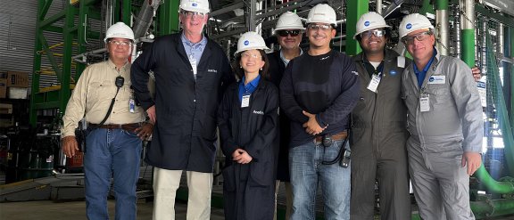 Une équipe de 7 personnes portant des casques avec le logo de Technip Energies sourient et posent pour la photo, avec Wei Cai (Directrice de la Technologie et de l'Innovation) au premier rang