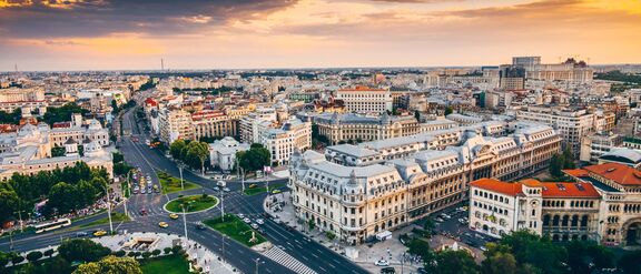 Aerial view of Romania at sunset, showing historic buildings, wide boulevards and busy intersections.