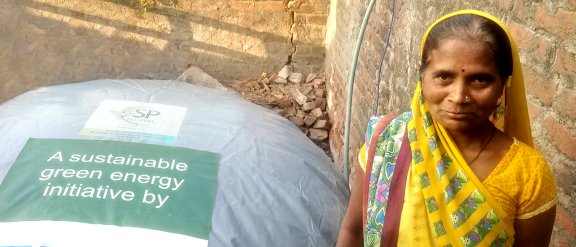 Une femme indienne se tient à côté d'un grand sac de biogaz, promouvant une initiative d'énergie verte durable dans sa communauté