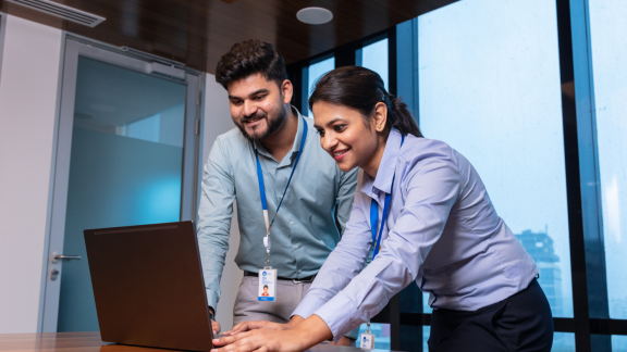 A man and a woman standing in front of a laptop