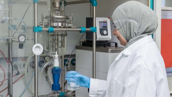 Woman in protective clothing conducting experiments in a laboratory.
