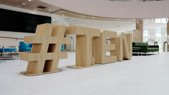 Large wooden sculpture reading #T.EN in Origine's reception