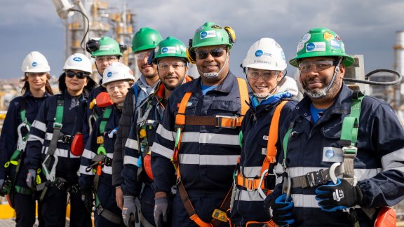 A team of workers facing the camera, with the construction site in the background
