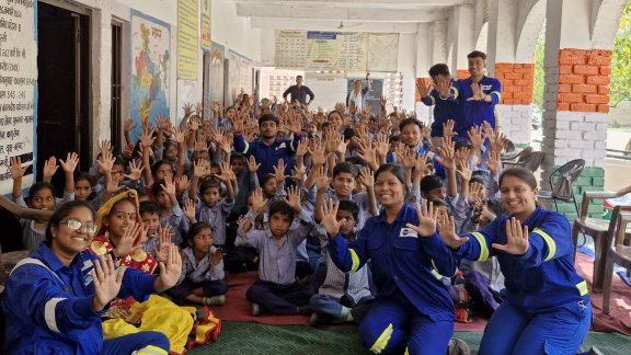A crowd of people smiling and raising their hands to celebrate Seed of Hope CSR program in India