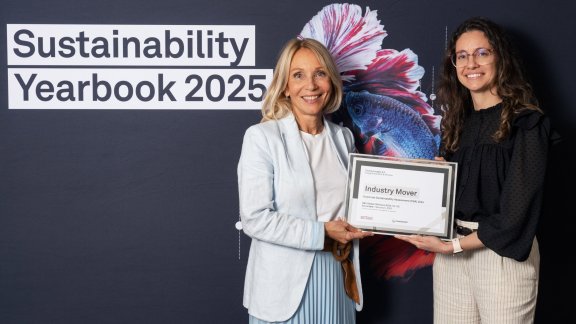 La Vice-Présidente Sustainability et la Sustainability Manager de Technip Energies sourient en tenant ensemble un document "Industry Mover" (moteur de l'industrie), symbolisant l'engagement de Technip Energies pour le développement durable