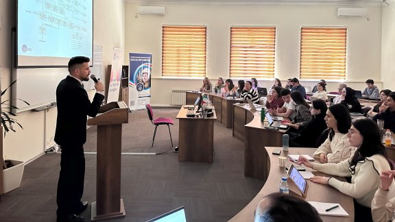 A speaker presents the Baku Master technology transfer program to an engaged audience of students.