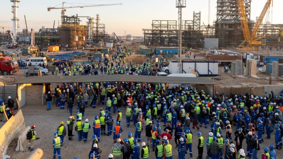 A crowd of workers on a construction site in Egypt, with cranes in the background