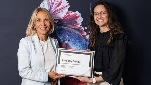 Technip Energies VP Sustainability and Sustainability Manager smiling while holding together a document "Industry Mover", recognizing Technip Energies’ commitment to sustainability