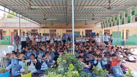Group photo of school kids raising both hands and smiling