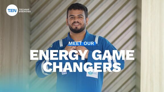 “Person in a blue industrial uniform standing in front of a patterned wall with the text ‘Meet Our Energy Game Changers’ displayed.”