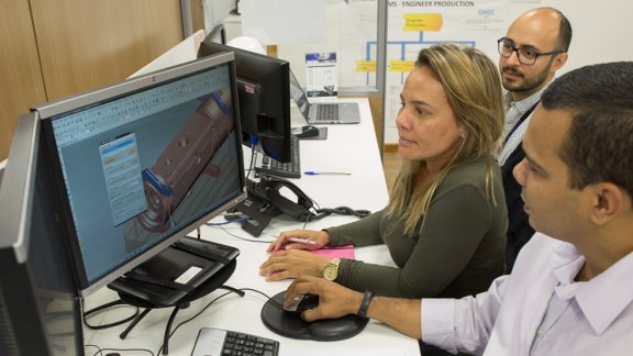 Une équipe collabore à un bureau, travaillant sur un projet d'ingénierie avec plusieurs écrans et équipements de bureau