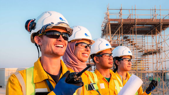Four NFE employees wearing coveralls and PPE pose for the camera