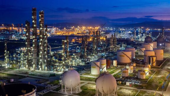 Raffinerie de pétrole et complexe pétrochimique illuminés au crépuscule, avec tours de traitement et réservoirs de stockage